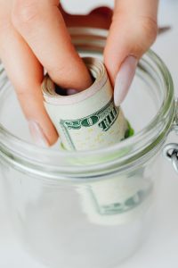 Stack of US dollar bills with a measuring tape showing a large amount.
