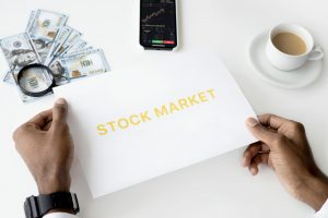 Two hands sifting through a pile of money, representing diversification hurting a portfolio.